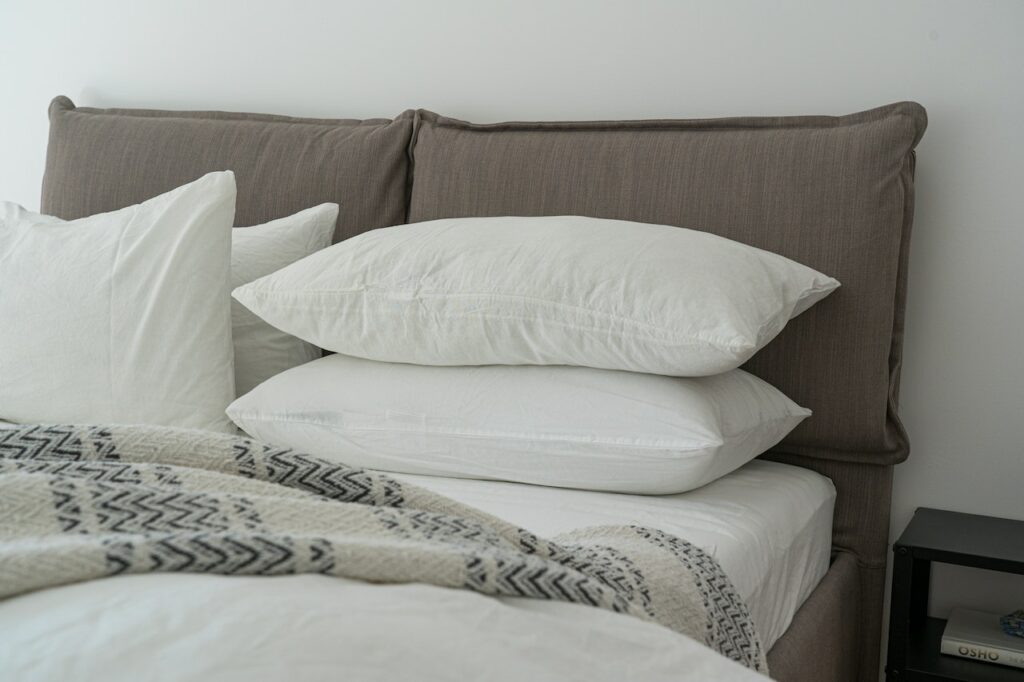 Travesseiros brancos empilhados sobre uma cama de casal.